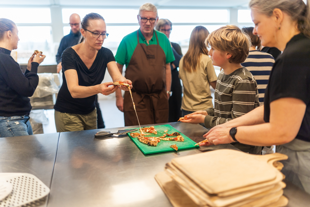 Kursister arbejder med pizza ved bordet på pizzakursus